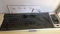 Lenovo wireless keyboard and mouse in original packaging with protective plastic on keyboard and accessories visible.