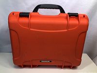 Front view of orange Nanuk 910 hard case showing minor front scuff and black handle