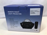 Photo of the sealed product box showing the remote night light star projector with remote control. Box lists functionality and features of the device.