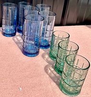 Nine tall drinking glasses arranged on a surface, in blue and green colors with Manchester Tartan pattern.