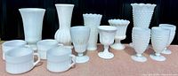 Full view of all milk glass pieces showing cups, goblets, vases with varied textures.