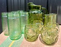 Front view showing the large textured green jug and groupings of two types of green glasses showing their unique textured patterns
