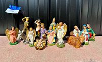 Photo showing full set of around 15 handpainted Italian creche figures including baby Jesus, Mary, Joseph, angels, shepherds, wise men, and animals for Christmas manger display.