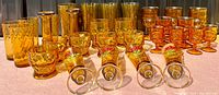 Wide front view showing diverse assortment of vintage amber glassware including goblets, tumblers, textured cups, and footed glasses.