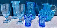 Full view of all blue glassware, including Fenton Hobnail pitcher, additional blue pitchers, vases, and various glasses