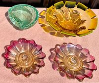Four handmade Murano glass pieces and two pink Federal Glass sunburst candle holders arranged on beige surface.