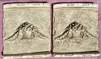 Pair of rectangular wall decor panels side by side on a reddish surface showing identical ancient Roman style floral basket reliefs with ornamental borders.