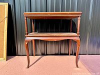 Front view of the walnut two-tier occasional table showing the curved legs and lower tier shelf.