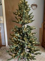 Full view of one artificial lighted tree standing assembled with lights lit