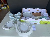 Overview of all items: mugs, plates, serving bowl in grape crate