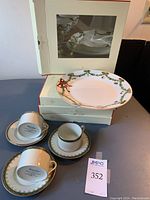 Photo showing Star Fluted Christmas dinner plate on top of box with cup and saucer sets arranged below