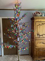 Full view of the 8-foot pre-lit artificial winterberry tree decorated with multi-colored LED sugar plum lights.