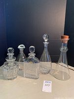 Full view of 4 glass decanters and 1 wine carafe, various shapes and styles, clear glass