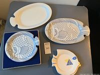 Full set of 5 fish-shaped plates shown on table including white and blue line design plates