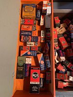 Open toolbox showing organized vintage tubes from GE, RCA, Westinghouse, National Union, and Raytheon in original boxes inside orange and gray toolbox.
