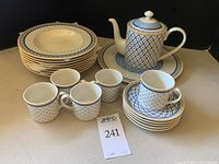Full set of dishes including plates, teapot with lid, sugar bowl with lid, tea cups and saucers, and soup bowls arranged on table showing pattern and condition.