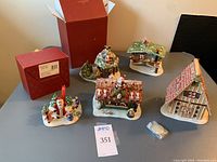 Five ceramic Christmas village buildings displayed with their original boxes and tea light holders, showcasing the lot contents