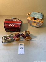 Overview of all three items: vintage fire engine toy, ceramic birdhouse, child’s accordion