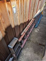 Photo of all three ladders positioned against a wood fence showing scale and condition.