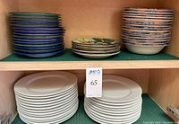 Photo showing stacks of various plates and bowls including green and blue Furio salad plates, handpainted Portuguese Favanol salad plates, and Crate & Barrel white dinner plates.