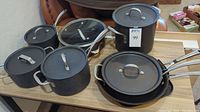 Photo showing multiple Calphalon pots and pans displayed on a table including sauce pans, Dutch ovens with lids, fry pan and griddle.