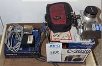 Overview photo showing the Olympus Camedia camera alongside a red and black camera case, charger, cables and original box.