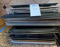 Stack of assorted cookie sheets and baking pans in various conditions with some wear.