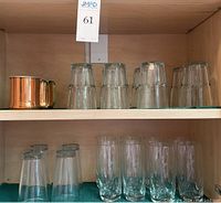 Two copper Mule mugs and multiple sizes of water glasses on shelves, showing item assortment and quantity.