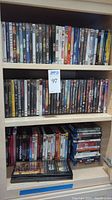 Top and middle shelves showing various DVD and Blu-ray movie titles arranged vertically and some stacked horizontally, displaying movie titles clearly.