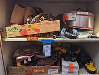 Full view of shelving unit with tool belts, gloves, power tools, hardware in cardboard boxes