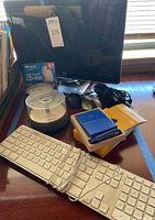 Photo of HP monitor, Apple keyboard, wireless mice, WD external hard drive, and CD-RW discs all placed on a desk.