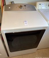Front view of white Kenmore Series 700 electric dryer with a tinted glass door and top control panel.