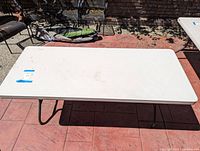Top view of white folding table, showing entire surface and legs underneath.