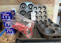Photo of baking pans, cookie cutters, foil baking cups, cake pan and cookie sheet arranged together showing all items in lot