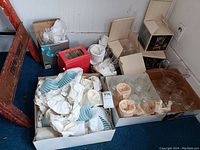 Photo showing boxed and wrapped blue frosted cocktail glasses along with stacked clear glassware and a clear pitcher.