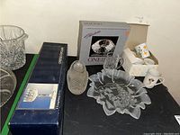 Photo showing two crystal serving dishes, one in box, a clear crystal mug, several ceramic mugs, and one boxed set of Longchamp glasses with a crystal bowl partially visible.