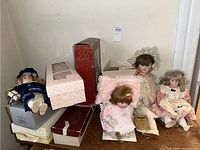 Six collector dolls arranged with boxes and pillow, showing variety of sizes and styles.