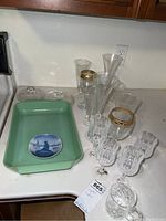 Overview showing the FireKing jadeite casserole dish, Royal Copenhagen plate inside it, and multiple pieces of crystal stemware displayed on countertop.