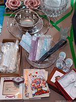 Image showing crystal bowls, Rockwell sterling overlay dish, fabric bridal garter belts, baby shoes porcelain with floral pattern, assorted greeting cards, and keepsakes.