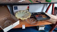 Group photo showing Murano footed bowl, crystal platters, Mikasa bowl in box, and other glass pieces on wooden shelf.
