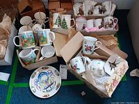 Overview of multiple boxed mugs and tea ware including Christmas themed, floral patterns, and boxed sets