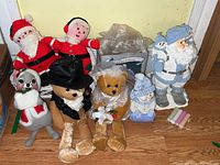 Overview of ceramic and knit Santa figurines, two teddy bears, Annalee Mouse doll, and pastel chalk sticks on floor