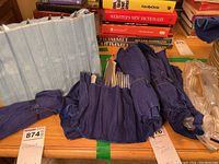 Multiple blue and light blue cloth rolls containing flatware and cutlery laid out on wooden surface