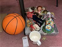 Overview image showing assorted items including a basketball, a collection of dolls, and a small white cup with a wind-up key near it.