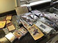 Photo showing multiple instruction manuals, brochures, six sets of insoles in clear plastic bags, and VHS/cassette tapes arranged on a countertop.