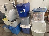 Overview of stacked plastic storage bins in various sizes and colors including blue, gray, clear, and beige bins.