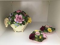 Wide view showing the Adderly floral china spray with pastel flowers in cream footed base on left and two Denton floral candle holders with colorful flowers on right.