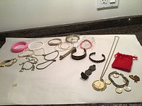 Full view of all jewelry laid out on white surface including bracelets, bangles, necklaces, and coin pendants