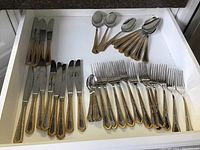 Full drawer with arranged flatware showing knives, forks, large spoons and small spoons arranged by type