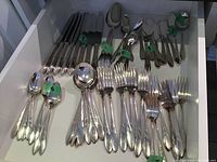 Drawer full of flatware pieces grouped and tagged with numbers showing quantity of each type.
